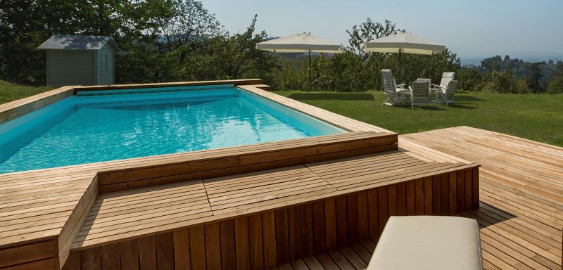 Piscina seminterrata a skimmer con rivestimento interno bianco ed esterno in legno