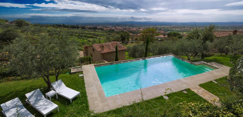 piscina a sfioro su terreno terrazzato color sabbia
