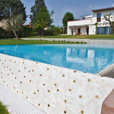 piscina rettangolare con cascata, scala, rivestimento bianco e mosaico