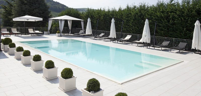 piscina rettangolare a bordo sfioro con scale e panche idromassaggio