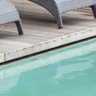 particolare di piscina con sfioro nascosto al di sotto della pavimentazione in legno