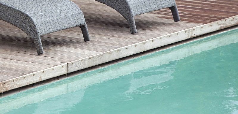 particolare di piscina con sfioro nascosto al di sotto della pavimentazione in legno