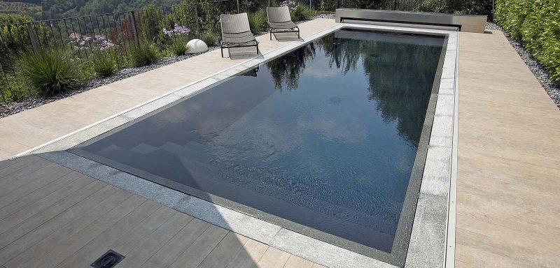 piscina grigia a sfioro con materiali pregiati e sistema trilogy