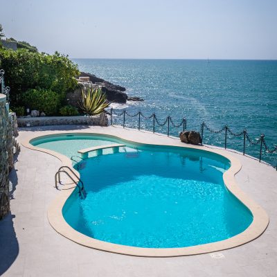 piscina a forma libera curvilinea, color sabbia con area spiaggetta per il relax e area più profonda per immergersi completamente