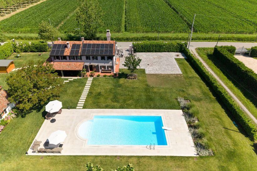 Una casa con piscina in giardino e pannelli solari sul tetto